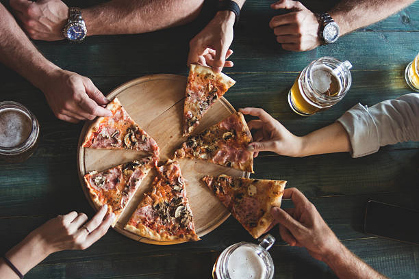 Pizza time! Friends having pizza in a restaurant. Top view. pub table top view stock pictures, royalty-free photos & images