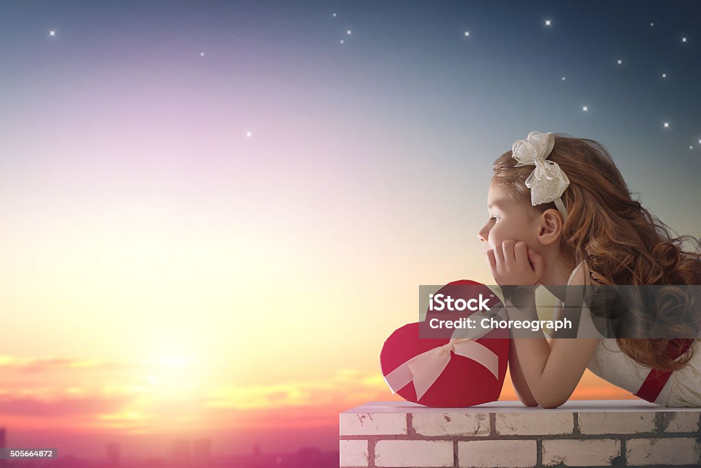 girl looking at the city Sweet child girl looking at the city at sunset. Little child girl has a gift box. Wedding, Valentine, love concept. Adult Stock Photo