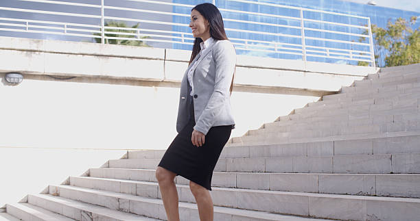 istock Serious woman walking up staircase 505667944