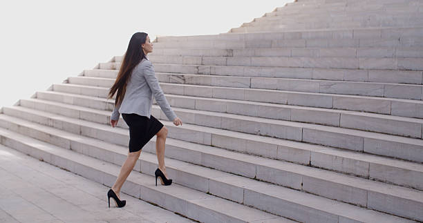 istock Serious woman walking up staircase 505667966