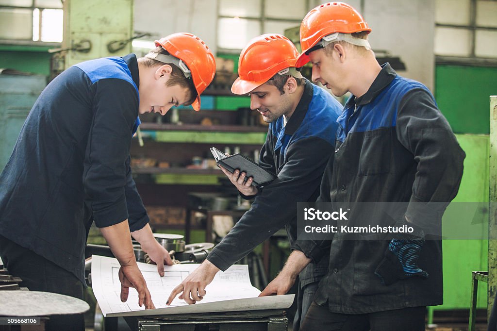 Männer mit Zeichnungen, die in eine alte Fabrik zu installieren - Lizenzfrei Berufliche Beschäftigung Stock-Foto