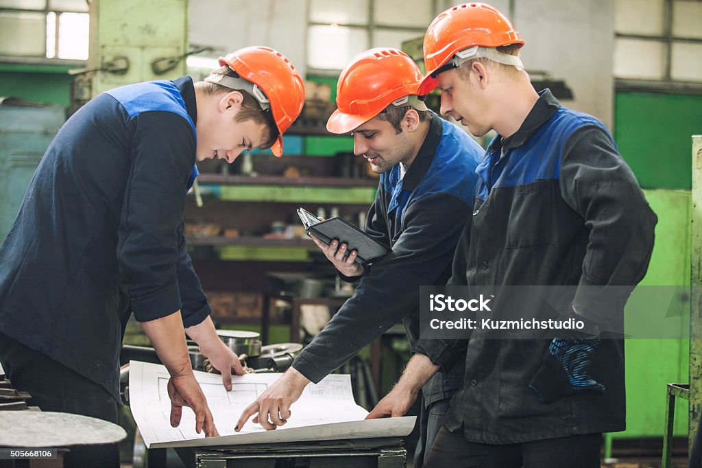 Uomini con disegni che lavora in una vecchia fabbrica di installare - Foto stock royalty-free di Occupazione