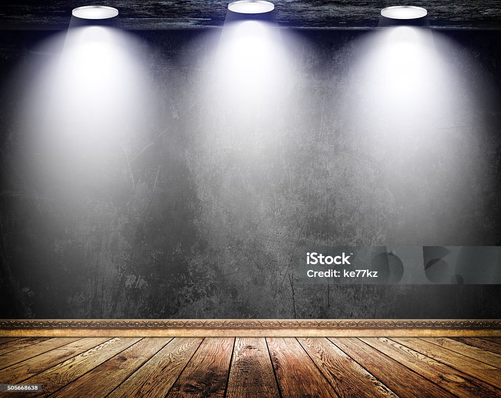 Black grunge wall with three lamps and old wooden floor. Old black concrete wall with three light sources  and old wooden floor with decorative wooden plinth. Abstract Stock Photo