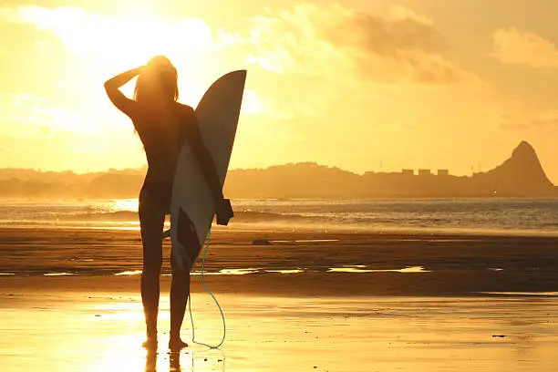 Beautiful girl standing with surfboard on the beach