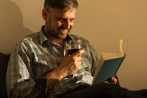 Smiling man reading interesting book in bed