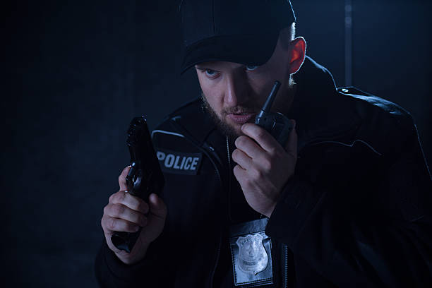 istock Policeman holding radio and gun 505673508