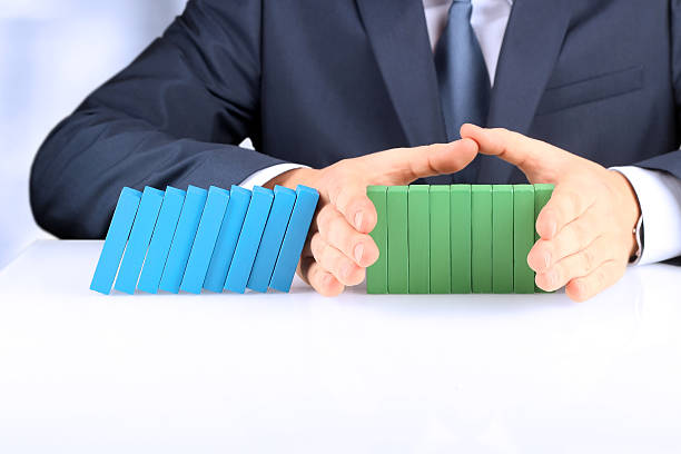 Planning, risk and strategy in business. The Effect Of Domino Planning, risk and strategy in business, businessman  holding   wooden blocks.  Businessman Stopping The Effect Of Domino depression behavior businessman economic depression stock pictures, royalty-free photos & images