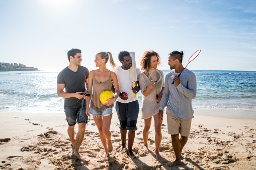 Group of young Australian people playing sports at the beach and looking very happy