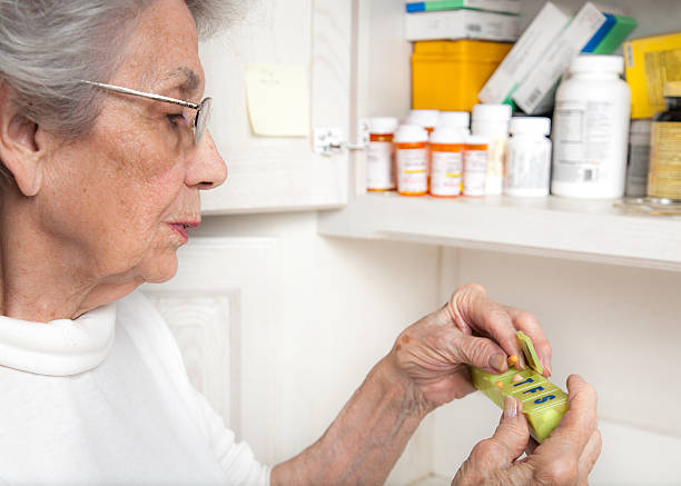 старший женщина, принимая лекарство от таблетница - medicine cabinet prescription pill bottle medicine стоковые фото и изображения