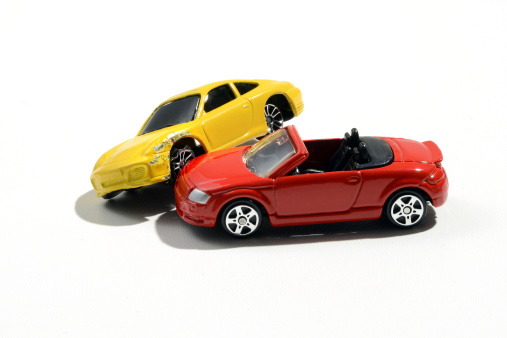 Two colorful metal toy model cars, one a bright yellow coupe and the second a vivid red sport car, over a white background