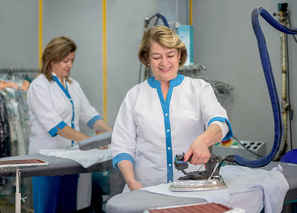 Happy women ironing clothes at a laundry service - small business concepts
