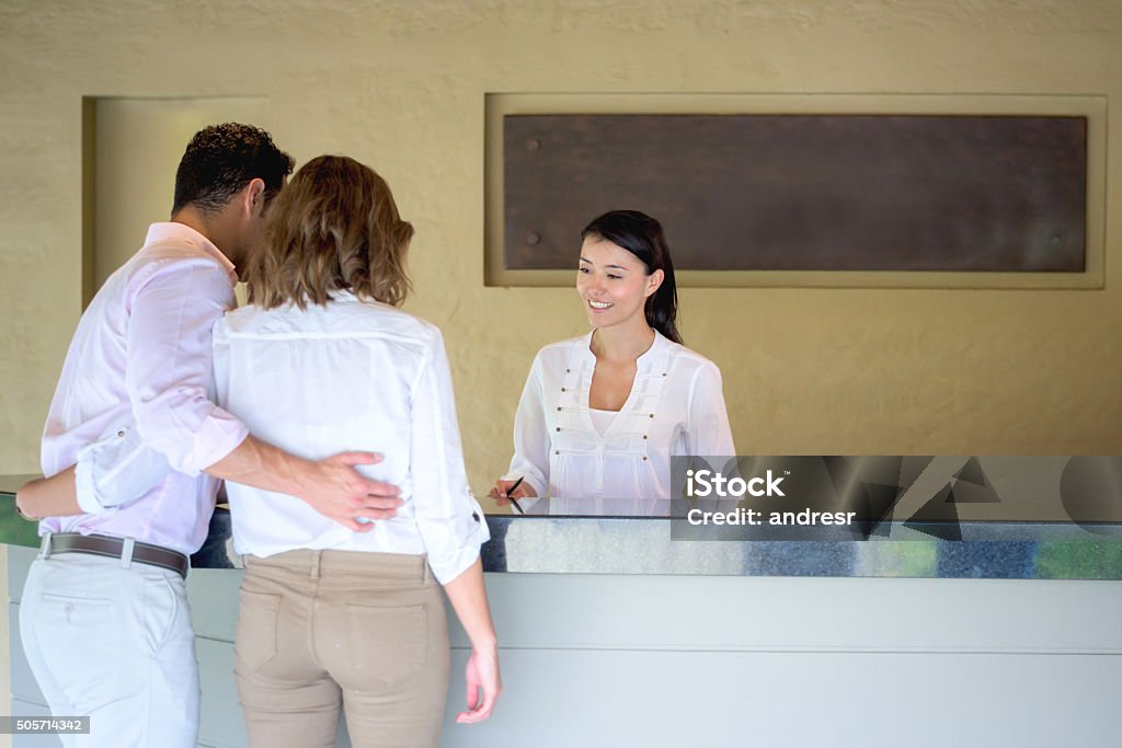 Couple checking in at a hotel Loving couple traveling and checking in at a hotel in the front desk Hotel Reception Stock Photo