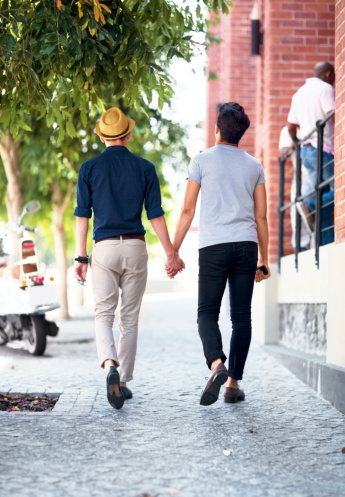 Shot of a young gay couple waling outdoors while holding hands