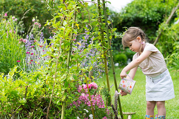 rapariga engraçada regar flores no jardim - blond hair carrying little girls small imagens e fotografias de stock