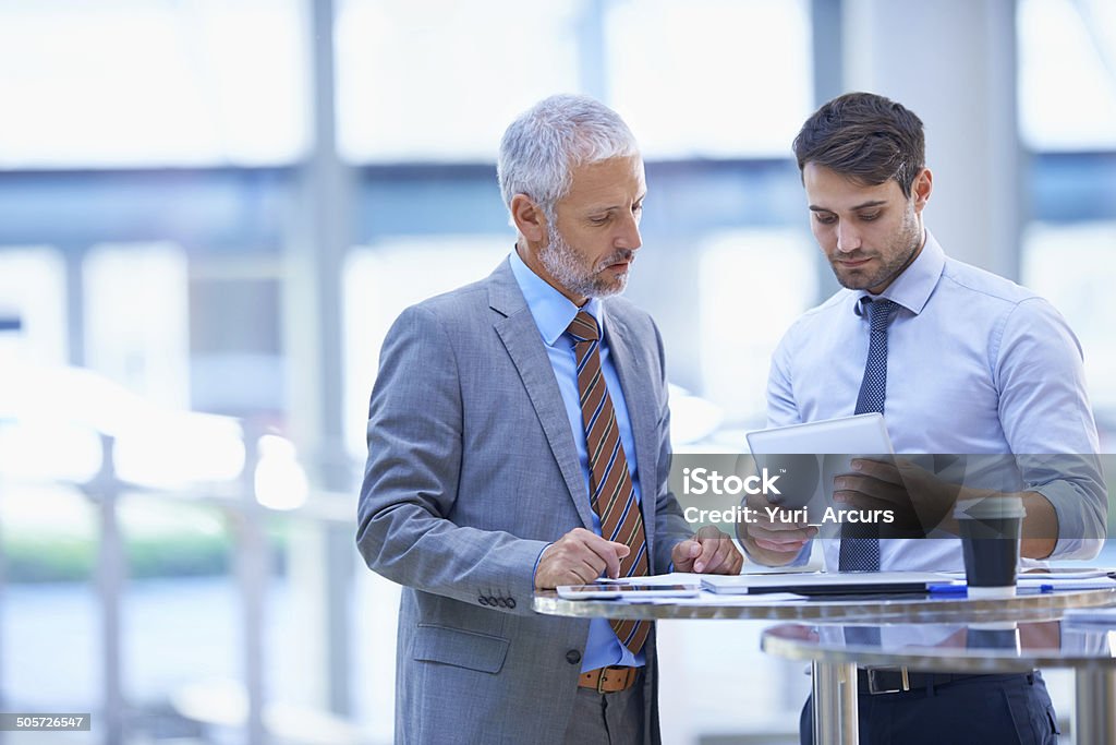 Analysing the day's reports Cropped shot of two colleagues using a tablet Two People Stock Photo