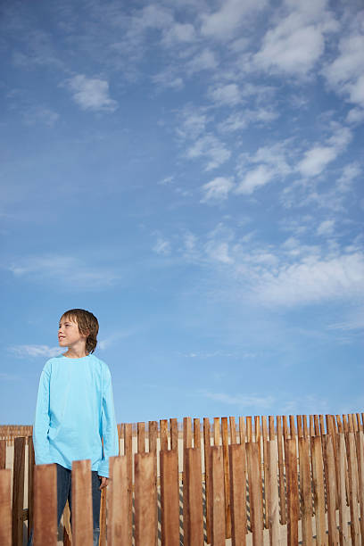 istock Boy Standing Between Wooden Fences On Beach 505727529