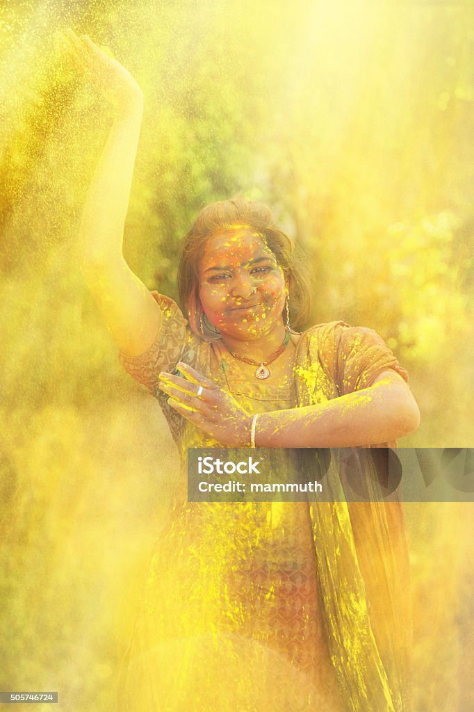 Young indian girl celebrating holi festival in India Happy indian woman dancing and throwing colorful powder during holi celebration in India. Adult Stock Photo