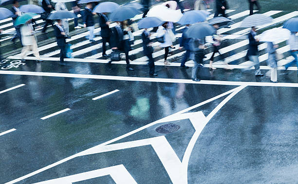faixa para pedestres ocupada cena em um dia chuvoso com borrão de movimento - umbrella parasol rain rush hour imagens e fotografias de stock
