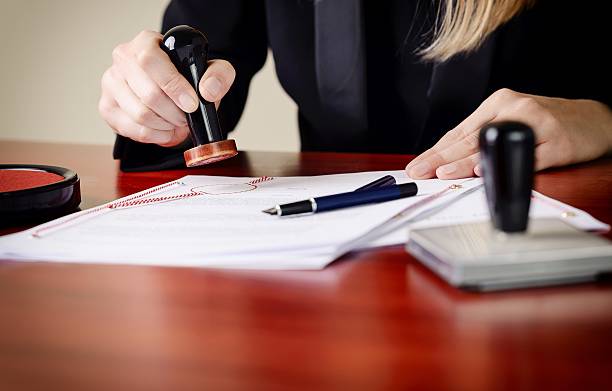 Closeup on notary's public hands stamping document. Closeup on notary's public hands stamping document. Notary public accessories legal document stock pictures, royalty-free photos & images