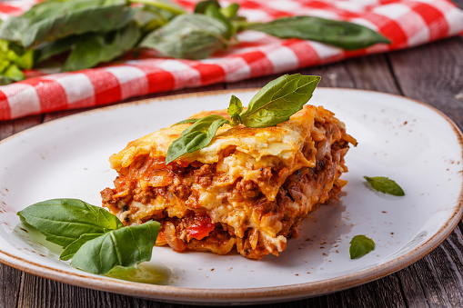 Traditional lasagna made with minced beef bolognese sauce and bechamel sauce  topped with basil leaves.