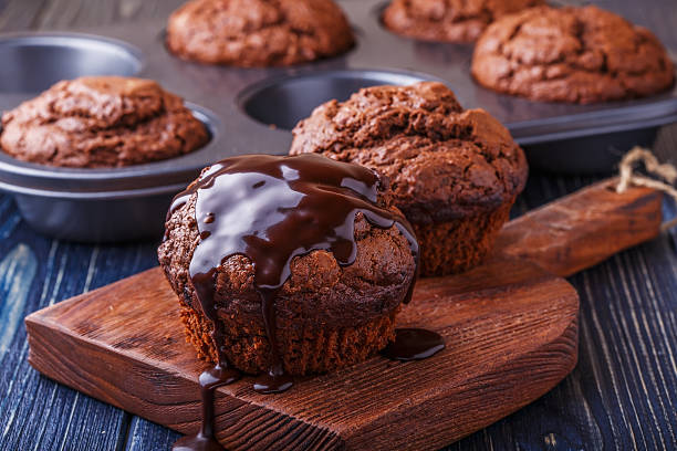 チョコレートマフィンにチョコレートシロップ濃い色の背景にしています。 - souffle dish ストックフォトと画像