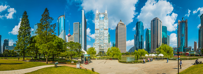 Shanghai, China - 7th October 2012: Families enjoying the carefully manicured parkland of Lujiazui Central Green Space, a tranquil leafy oasis surrounded by the gleaming skyscrapers of Pudong, Shanghai's futuristic financial district. Composite panoramic image created from nine contemporaneous sequential photographs.