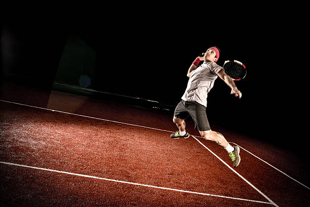 テニス選手措置：ジャンプスマッシュ - indoor tennis ストックフォトと画像