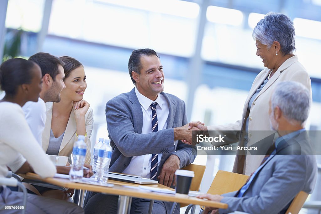 We're looking forward to working with you! A cropped shot of two businesspeople shaking hands at a meeting with colleagues Business Stock Photo