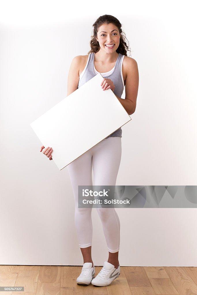 Young Woman with Blank Sign attractive young woman in exercise clothing holding a blank A4 sign Females Stock Photo