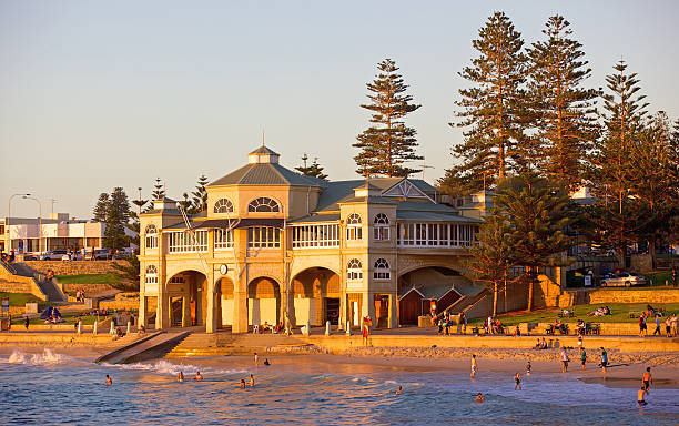 Cottesloe Beach Perth, Australia – April 25, 2011: Swimmers relaxing and bathing at sunset in front of the old pavillion at Cottesloe Beach in Perth, Western Australia. cottesloe beach stock pictures, royalty-free photos & images