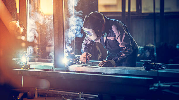 Industrial worker with welding tool Welder with protective equipment welding metal in small workshop. steel grinding stock pictures, royalty-free photos & images