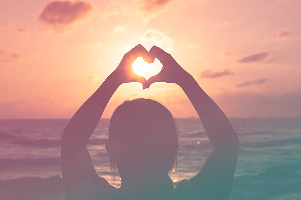 istock Love shape hand silhouette in sunset or dunrise period 505772446