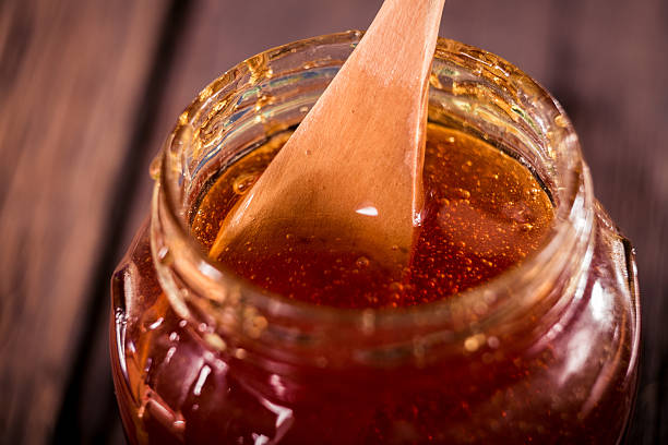 istock Honey dripping from a wooden honey dipper   on black background 505774874