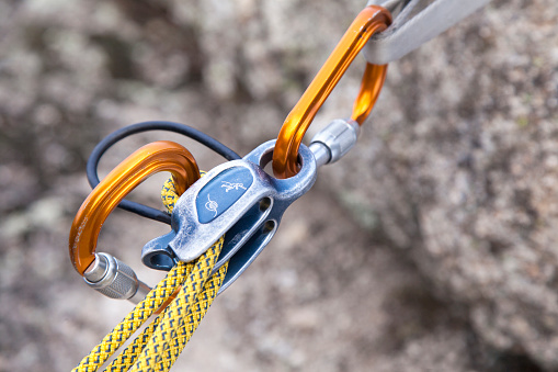 Climber teenage boy in protective helmet jumping on vertical cliff rock wall using rope Belay device, climbing harness in Paklenica canyon in Croatia. Active extreme sports time spending concept