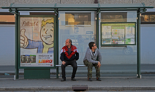 Graz, Austria - November 14, 2015: 2  men are waiting transport at the bus stop