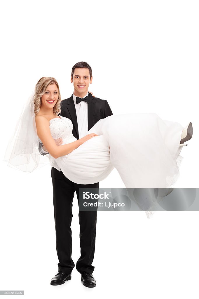 Young groom carrying a bride in his hands Full length portrait of a young groom carrying a bride in his hands isolated on white background Wedding Stock Photo