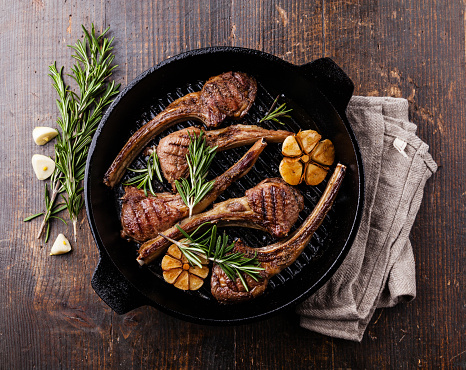 Roasted lamb ribs with rosemary and garlic on grill pan on dark wooden background