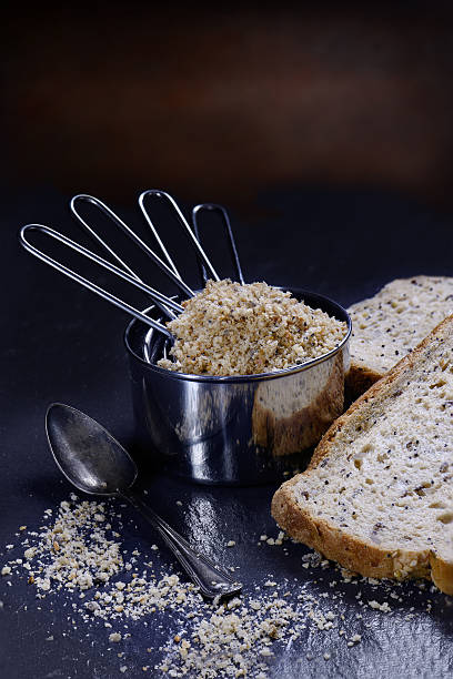 Breadcrumbs Freshly milled granary loaf breadcrumbs in steel measuring cups against a  rustic background. Concept image for cooking or food preparation. Generous accommodation for copy space. granary toast stock pictures, royalty-free photos & images