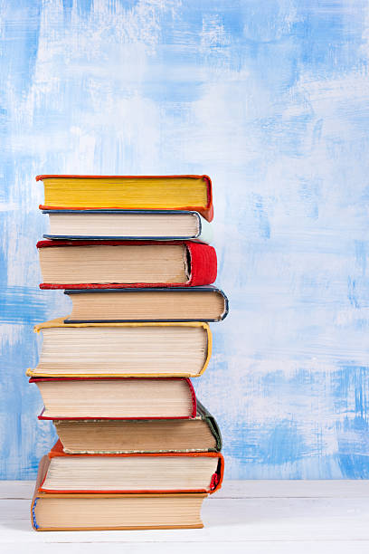 istock Stack of colorful hardback books, open book on blue background 505792382