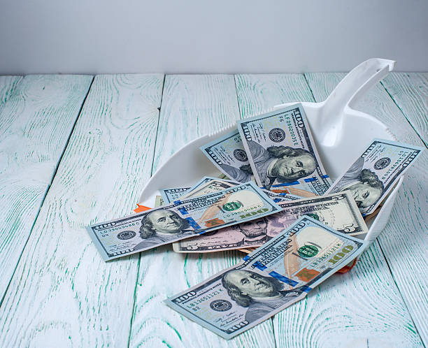 istock Dollars in garbage scoop on wooden background 505800266