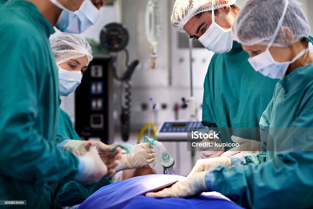 The incision is made Shot of a group of surgeons working on a patient in an operating room Accidents and Disasters Stock Photo