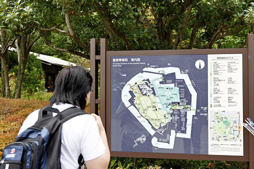 Tokyo,Japan - October 31,2010: Asian tourist is looking at the guide map of the East Gardens of the Imperial Palace. The Imperial Palace East Gardens are a part of the inner palace area and are open to the public throughout the year except on Mondays, Fridays, New Year ( (Dec 28 to Jan 3) and some special occasions. 