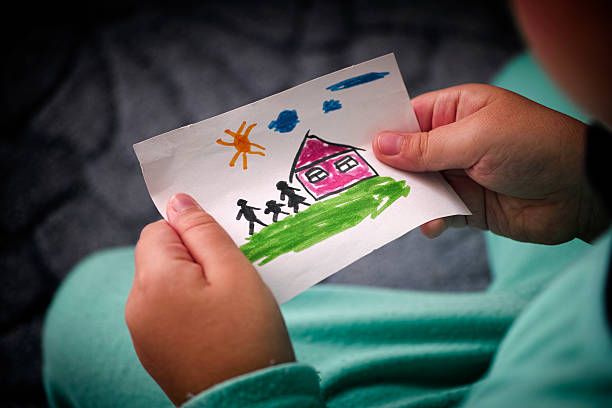 Child holds a drawn house with family Child holds a drawn house with family. Close up. Vignette. light at the end of the tunnel stock pictures, royalty-free photos & images