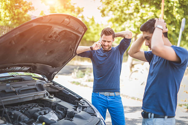 friends examining broken down car on sunny day - vehicle breakdown stockfoto's en -beelden