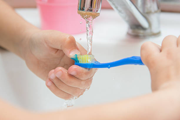 enfant nettoie brosse à dents sous l'eau courante, gros plan - smiling human teeth toothbrush moving up photos et images de collection