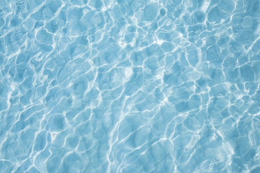 Turquoise pool water surface with ripples and waves on sunny day