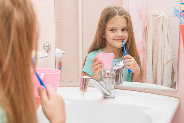 fille avec une brosse à dents et d'un verre - smiling human teeth toothbrush moving up photos et images de collection