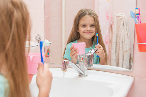 heureuse petite fille avec brosse à dents et tasse - smiling human teeth toothbrush moving up photos et images de collection