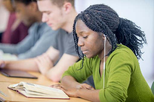 A multi-ethnic group of high school age students are sitting at their desks and are studying.
