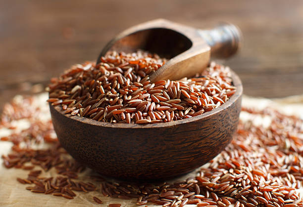 istock Uncooked Red rice in a bowl with a wooden spoon 505829712